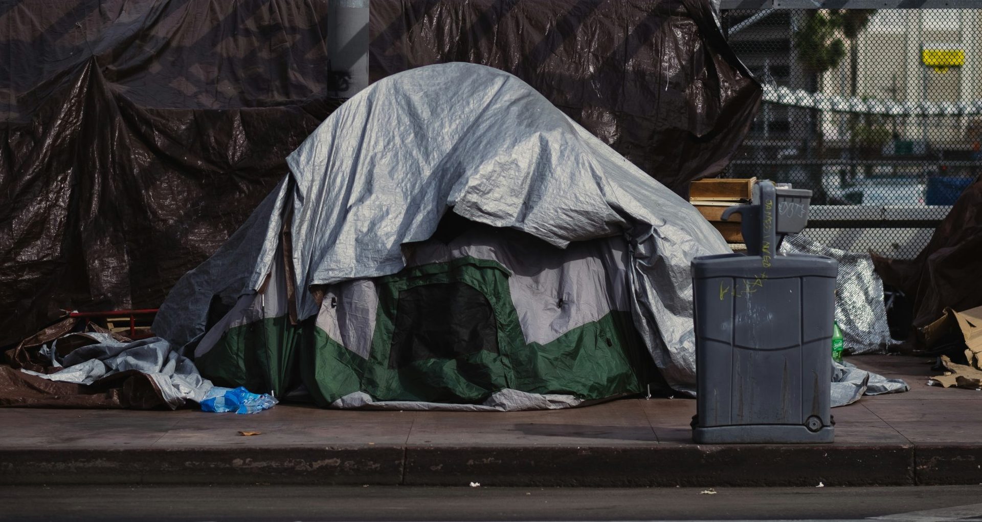 A tent outside in the middle of piles of rubbish.